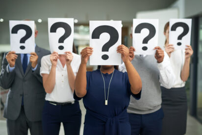 Shot of a group of businesspeople holding questions marks in front of their faces